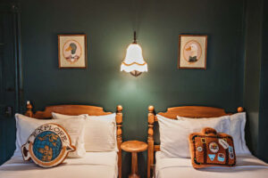 Two twin beds with travel-themed pillows and vintage decor.