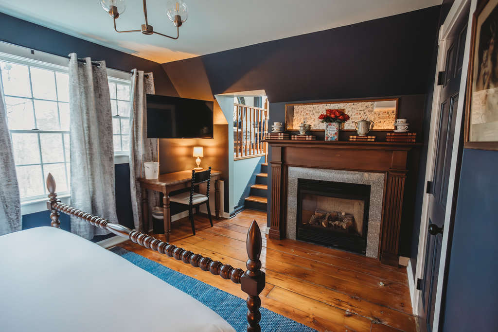 A welcoming inn room featuring a fireplace, TV, and wooden furniture.