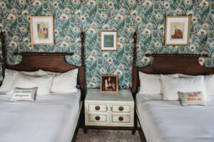 Two beds with decorative pillows and a nightstand between them.