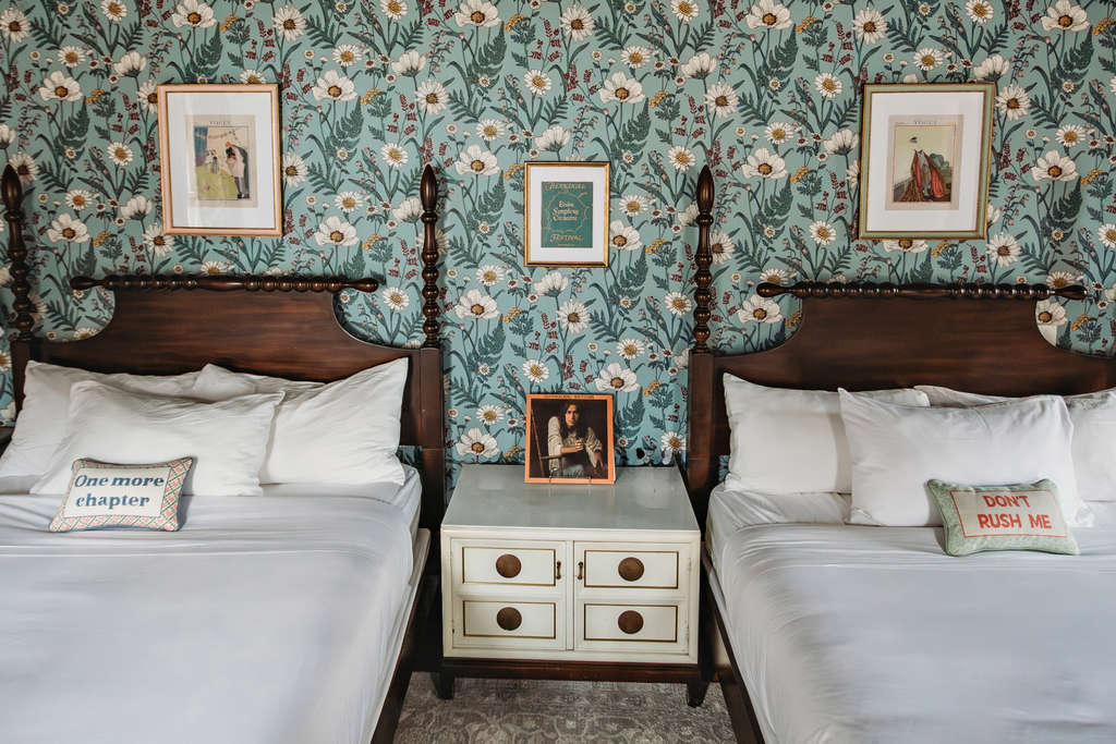 Two beds with decorative pillows and a nightstand between them.