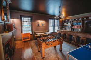 A stylish game room featuring a foosball table, bookshelves, and comfortable seating.