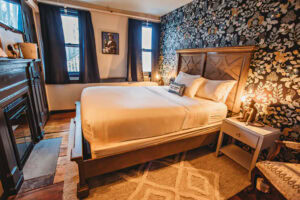 A welcoming hotel room featuring a large bed, floral wallpaper, and wooden furniture.