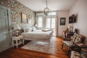 Cozy hotel room featuring floral wallpaper, vintage furniture, and natural light.