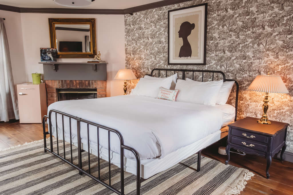 A stylish bedroom featuring a metal bed frame, artwork, and warm lighting.