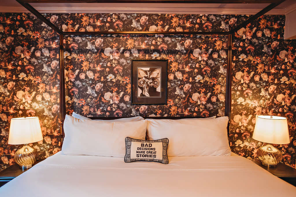 Cozy bedroom featuring floral wallpaper, bedside lamps, and decorative pillows.