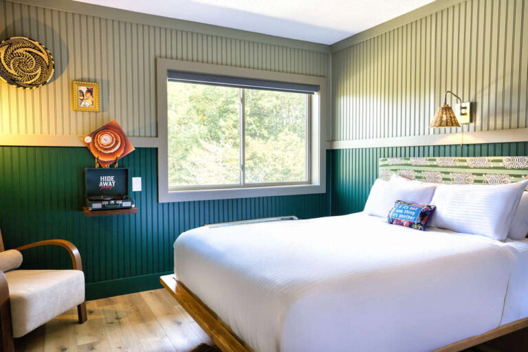 Bright hotel room with a large window overlooking greenery.