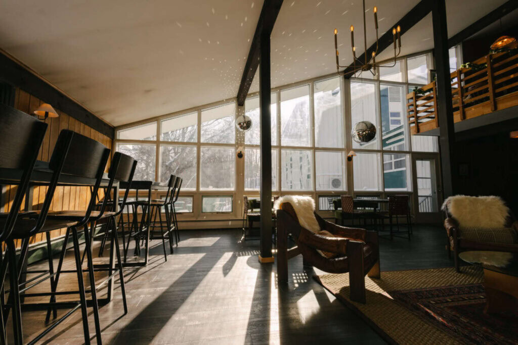 Bright interior of a lounge with large windows and mountain scenery.