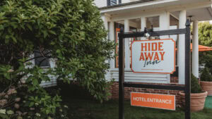 Hotel entrance sign with Hide Away Inn logo and orange details.