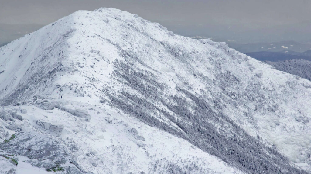 Majestic mountain peak covered in snow with cloudy sky background.
