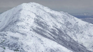 Majestic mountain peak covered in snow with cloudy sky background.