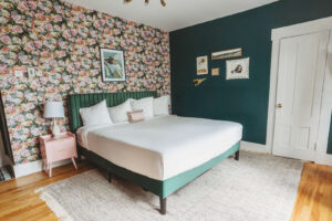 Comfortable bed with white linens and floral wallpaper in a modern bedroom.