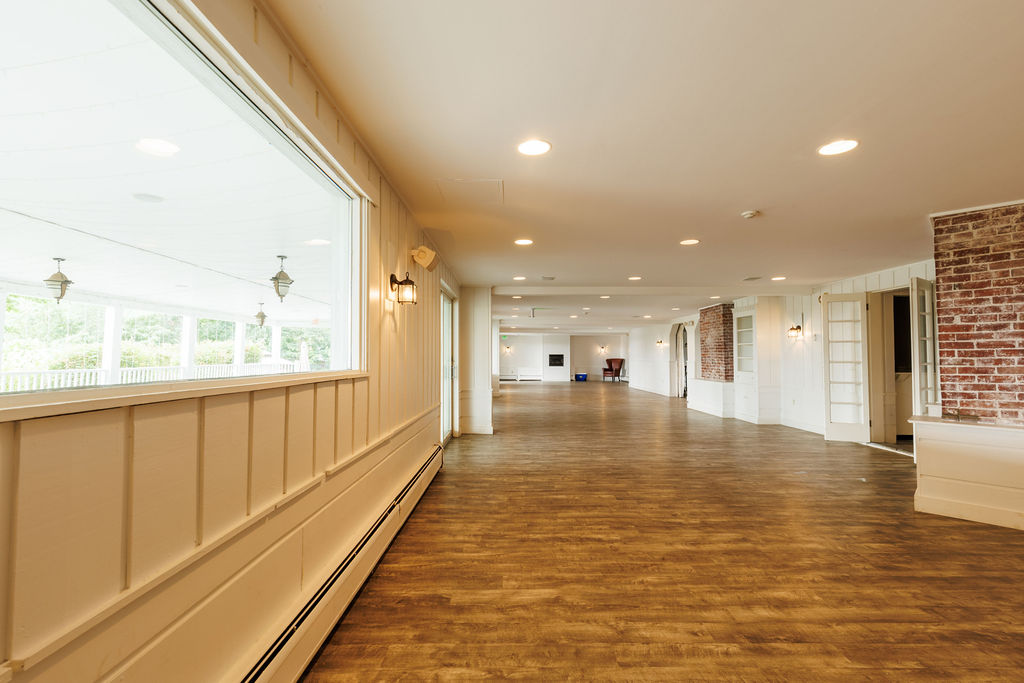 Large, empty event space with wood floors and brick accents at Hideaway Inn.