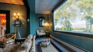 Indoor lounge with vintage furniture and a large window overlooking trees.