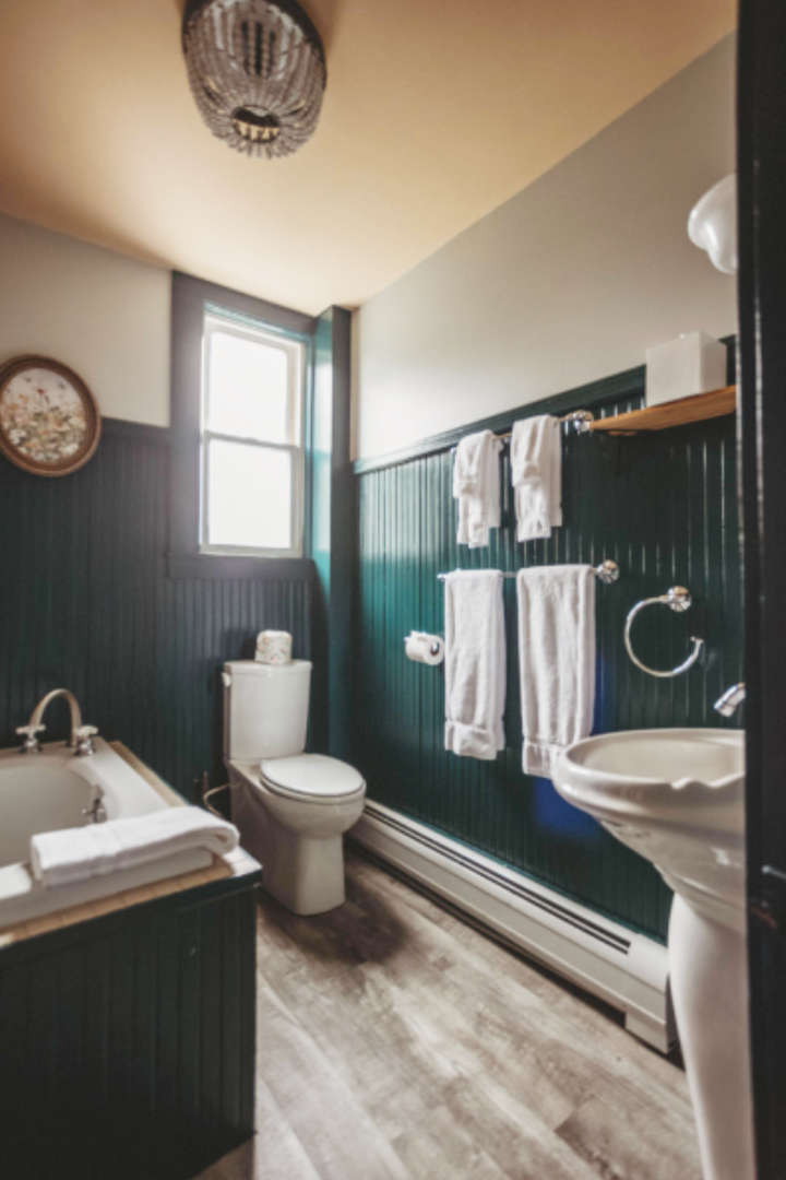Bathroom with dark green paneling, white towels, and a small window.