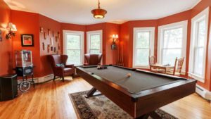 Bright game room with pool table, armchairs, and large windows.