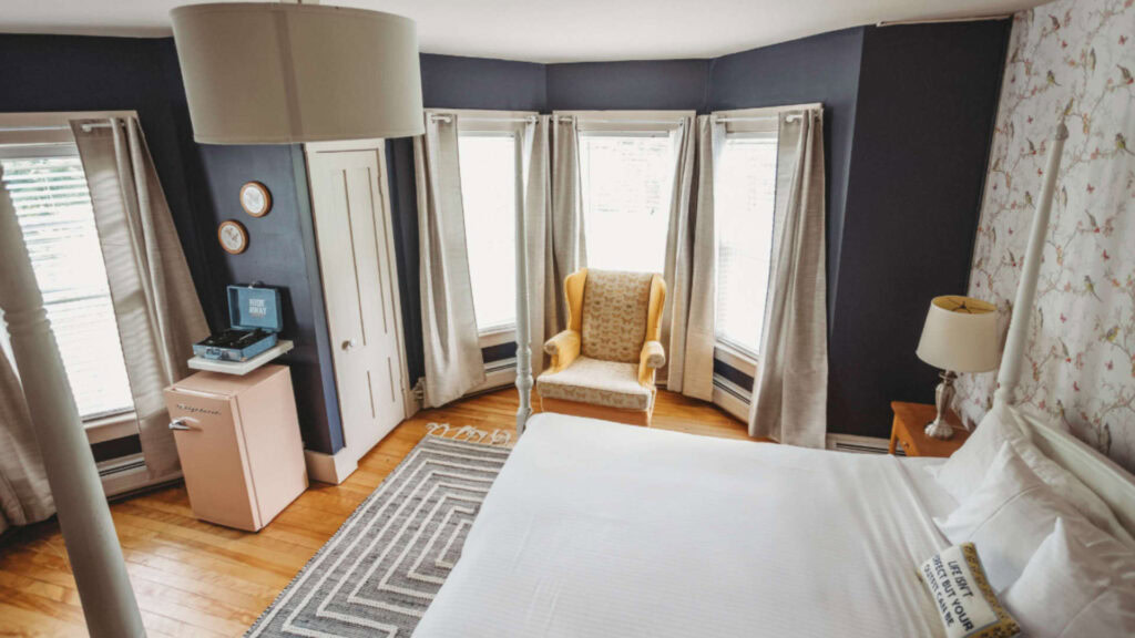 Bright hotel room with bay windows, armchair, and modern decor.