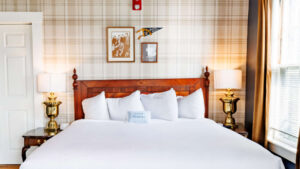 Comfortable bed with white linens and vintage lamps in a warmly decorated room.