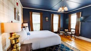 Comfortable bedroom with blue walls, large windows, and classic furniture.