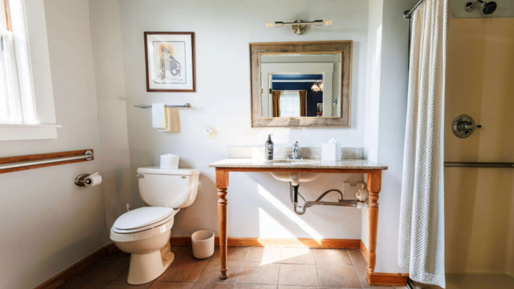 Clean bathroom with toilet, wooden vanity, mirror, and shower curtain.